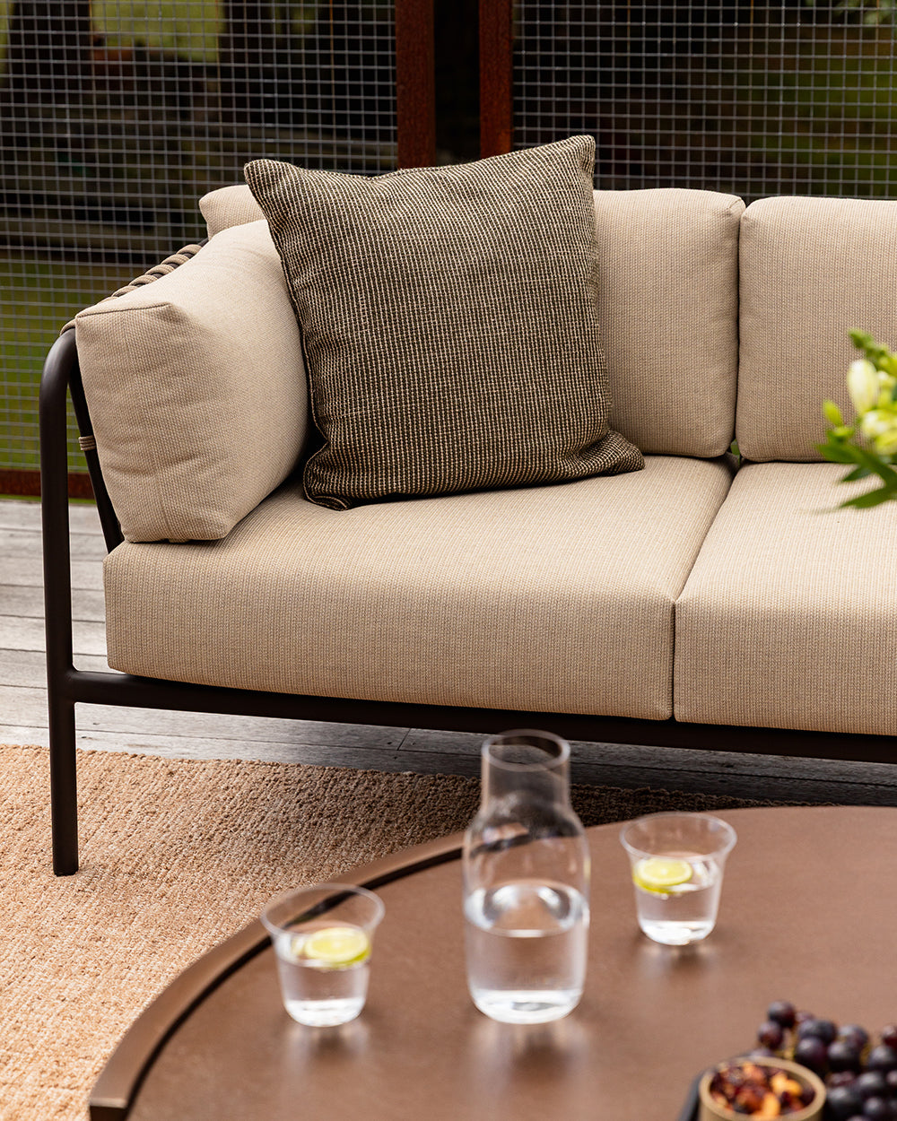 Baya Dune outdoor cushion in Mangrove styled on the corner of an outdoor sofa