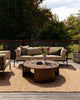 Baya Dune outdoor cushion in Mangrove styled on an outdoor sofa, wider view with a round coffee table
