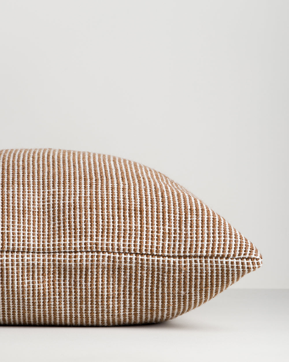Close-up side profile of the Baya Dune outdoor cushion in Tobacco, showing the corner point and piped edge