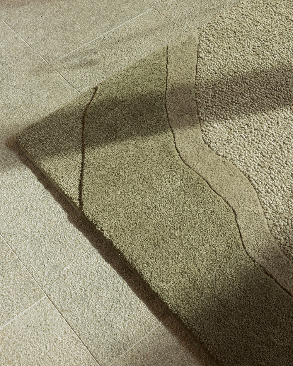 Baya Edgewater NZ wool floor rug in Pistachio, rectangle, close view of a corner in raking light showing the fine dark wave lines.