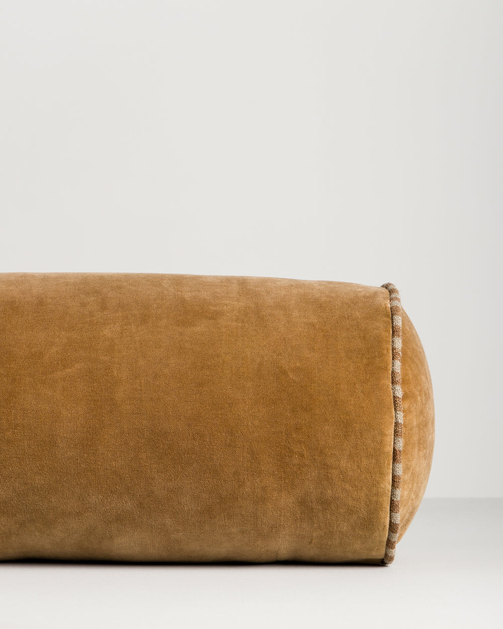 Baya Elliot cotton velvet bolster cushion in Butterscotch, close view of the velvet texture and striped piped end