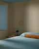 Baya Elliot cotton velvet bolster cushion in Butterscotch, on a bed in a styled bedroom corner