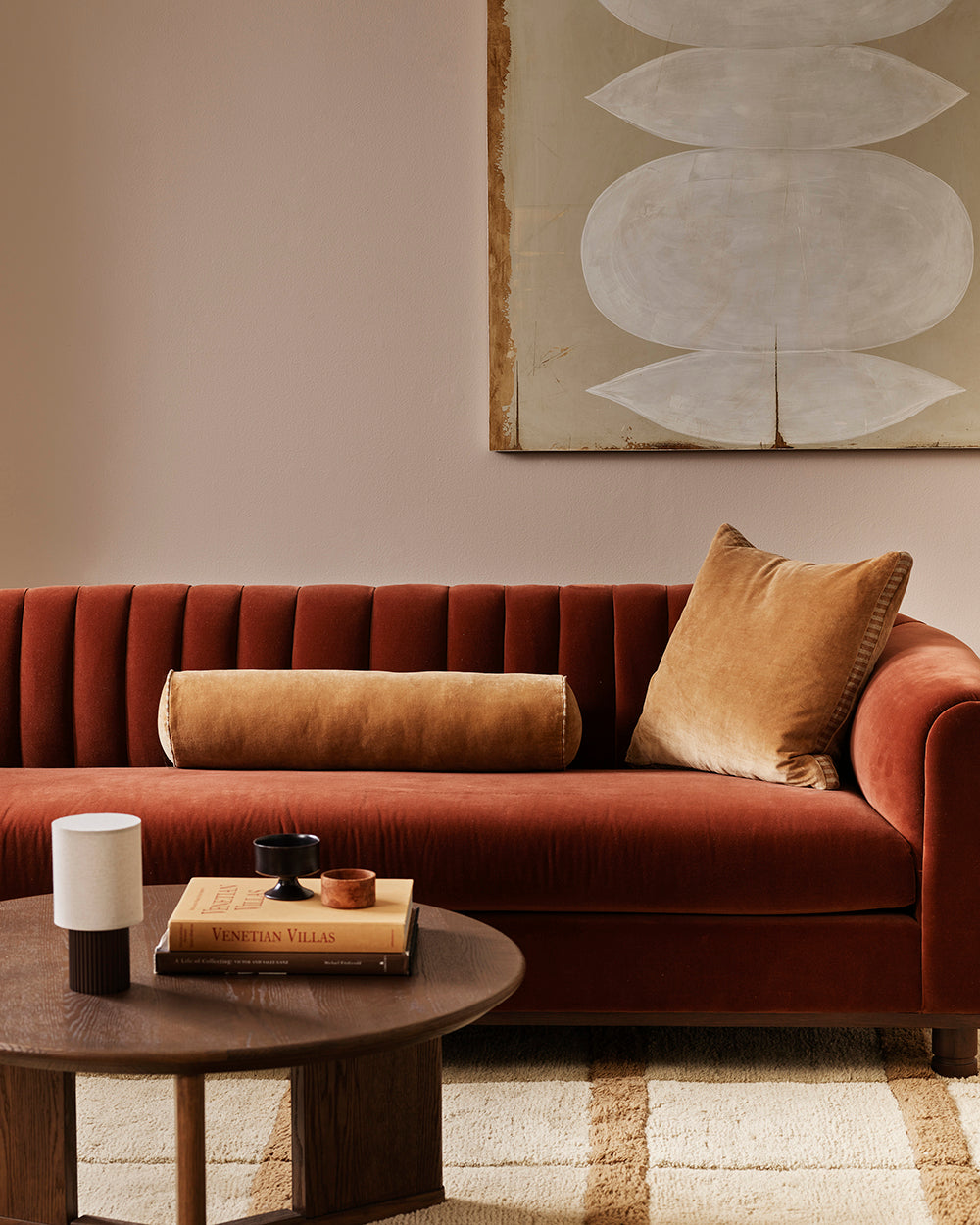 Baya Elliot cotton velvet bolster cushion in Butterscotch, styled on a rust velvet sofa with the matching Edward box cushion