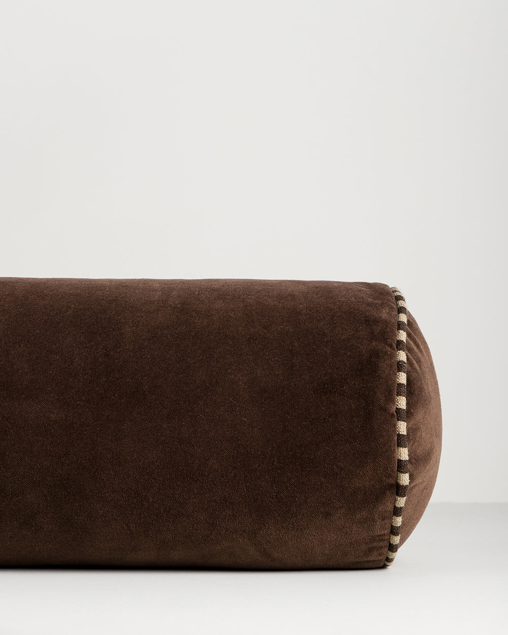 Baya Elliot cotton velvet bolster cushion in Chocolate, close view of the velvet texture and striped piped end
