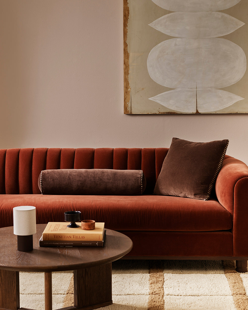 Baya Elliot cotton velvet bolster cushion in Chocolate, styled on a rust velvet sofa with a matching square cushion