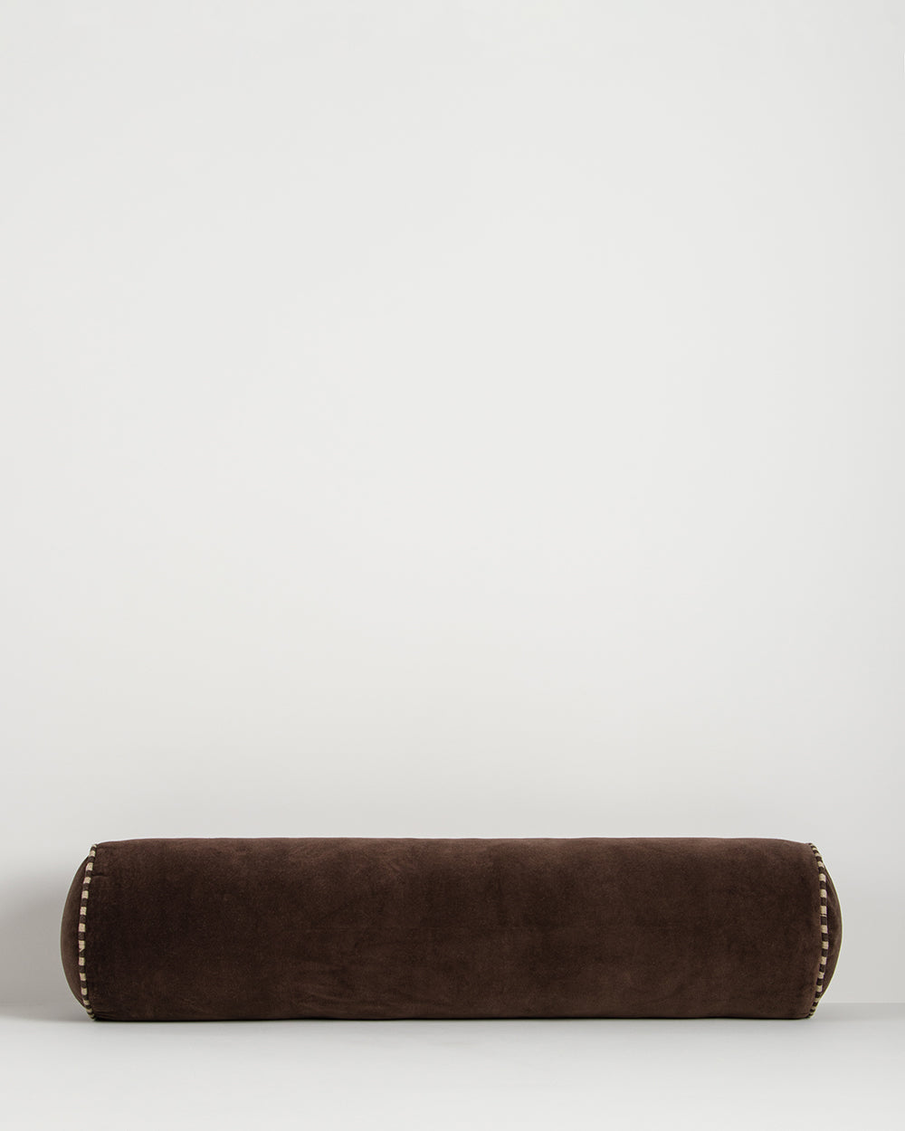 Baya Elliot cotton velvet bolster cushion in Chocolate on a plain background