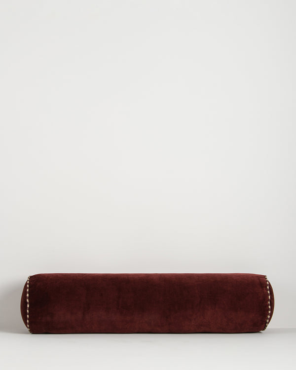 Baya Elliot cotton velvet bolster cushion in Oxblood on a plain background