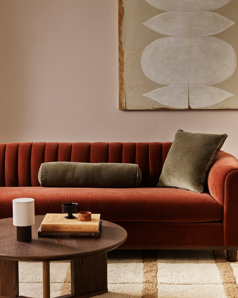 Baya Elliot cotton velvet bolster cushion in Thyme, styled on a rust velvet sofa with a matching square cushion