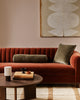 Baya Elliot cotton velvet bolster cushion in Thyme, styled on a rust velvet sofa with a matching square cushion