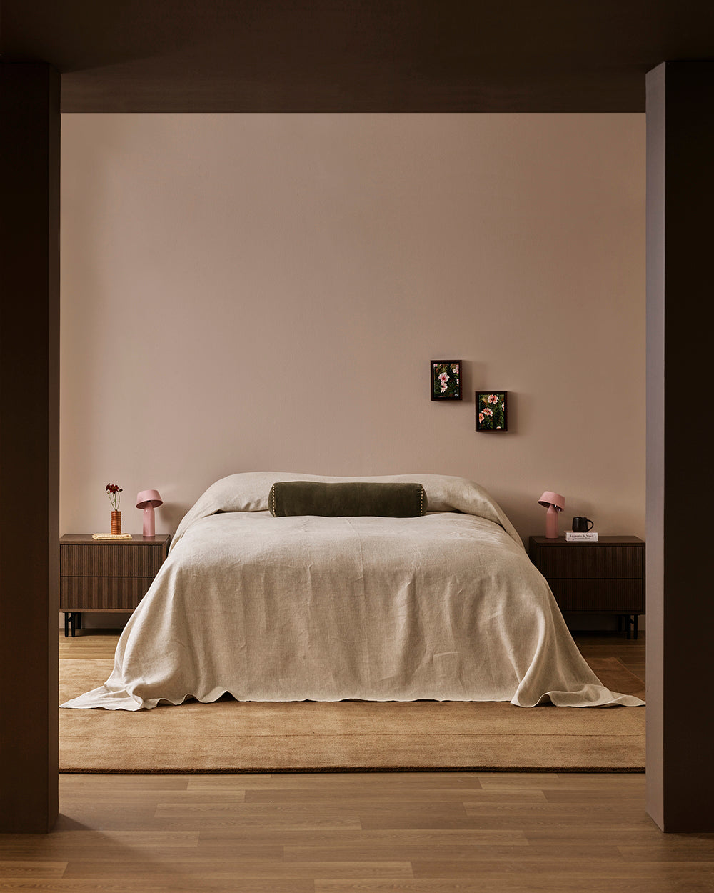 Baya Elliot cotton velvet bolster cushion in Thyme, on a bed in a styled bedroom