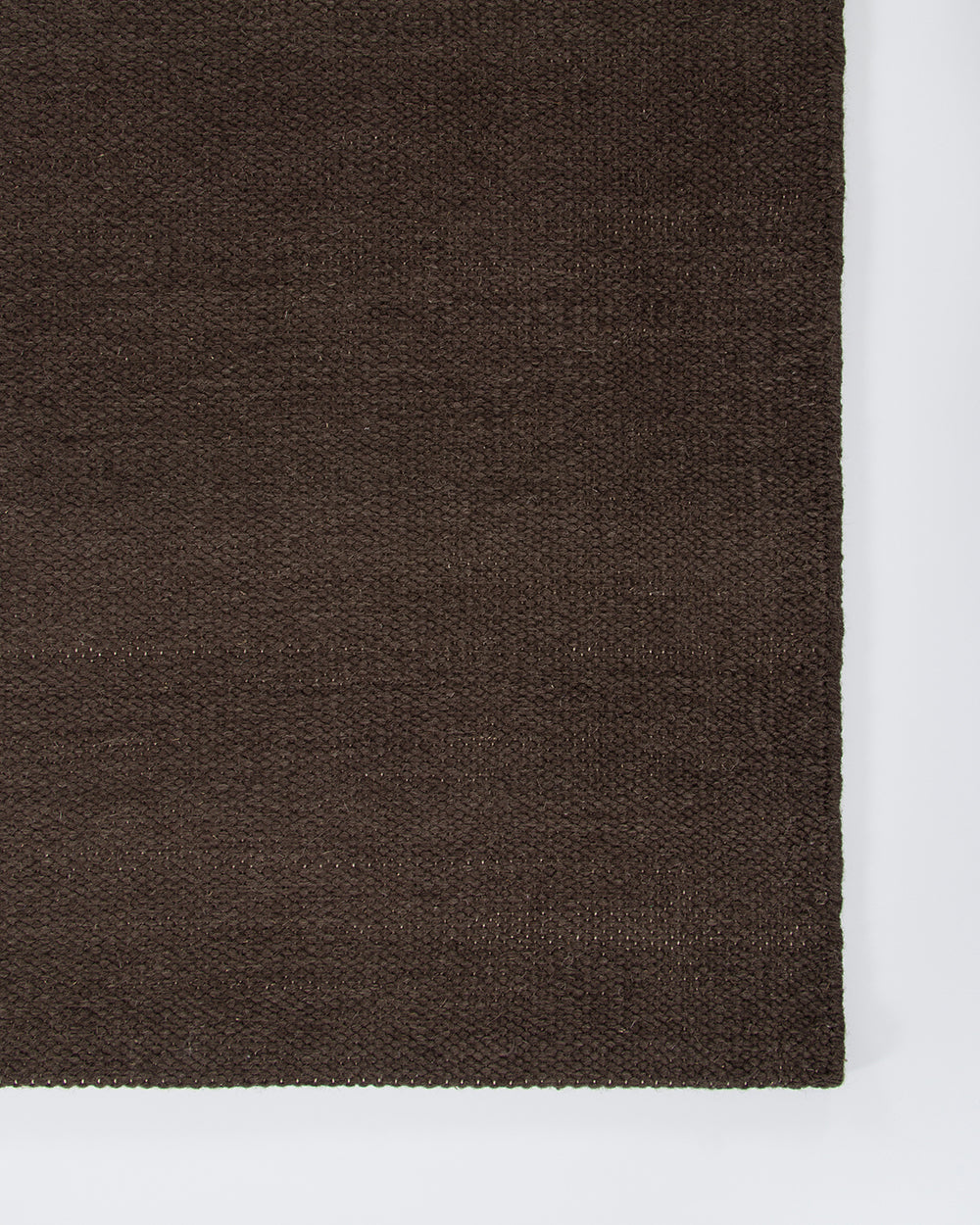 Baya Fairmont NZ Wool Floor Rug in Bracken, close view under a dining table set with a vase of flowers and a napkin