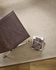 Baya Fairmont NZ Wool Floor Rug in Limestone, overhead view beside a leather chair with books
