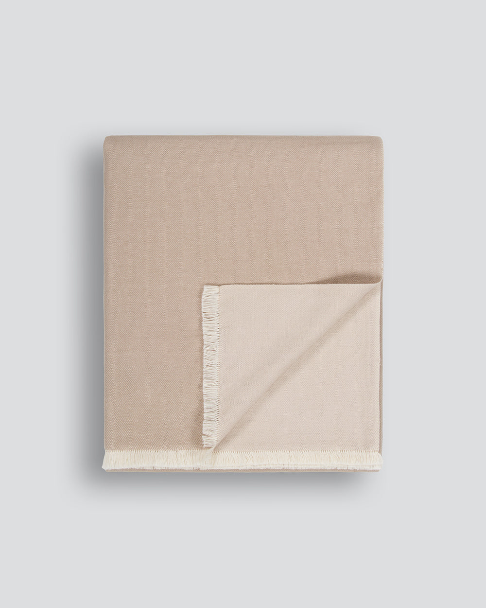 Baya Langford throw in ecru, a warm neutral, folded flat to show the fringed edge and cream reverse.