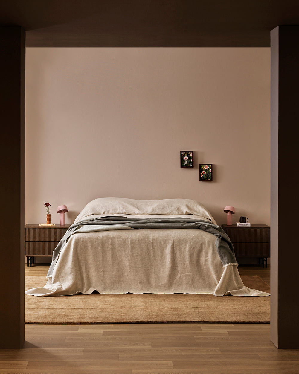 Baya Langford throw in khaki draped over a bed, seen through a doorway in a dark bedroom.