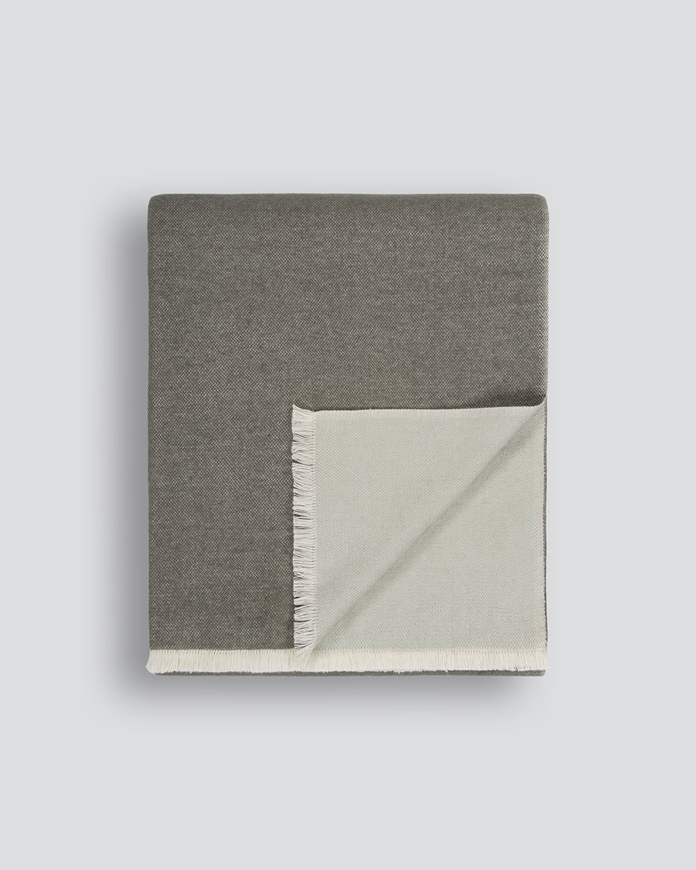 Baya Langford throw in khaki, a dusky green, folded flat to show the fringed edge and pale sage reverse.