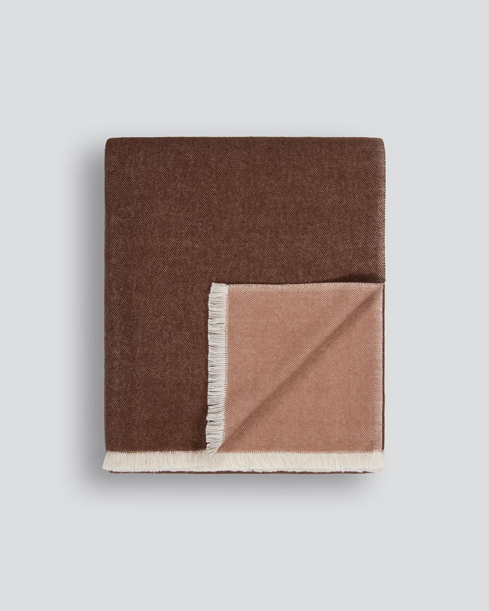 Baya Langford throw in raisin, an earthy red-brown, folded flat to show the fringed edge and beige reverse.