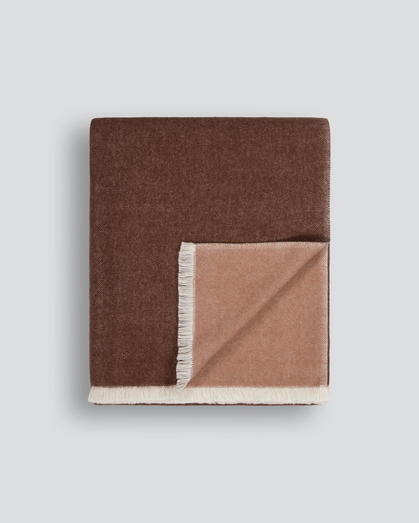 Baya Langford throw in raisin, an earthy red-brown, folded flat to show the fringed edge and beige reverse.