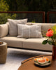 Baya Shore outdoor lumbar cushion in Almond styled on an outdoor sofa, with a second textured cushion in the background