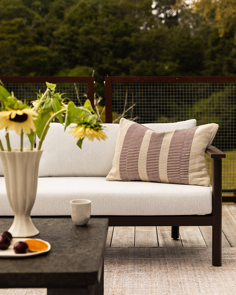 Baya Solar Outdoor Lumbar Cushion in Claret, styled on an outdoor sofa.