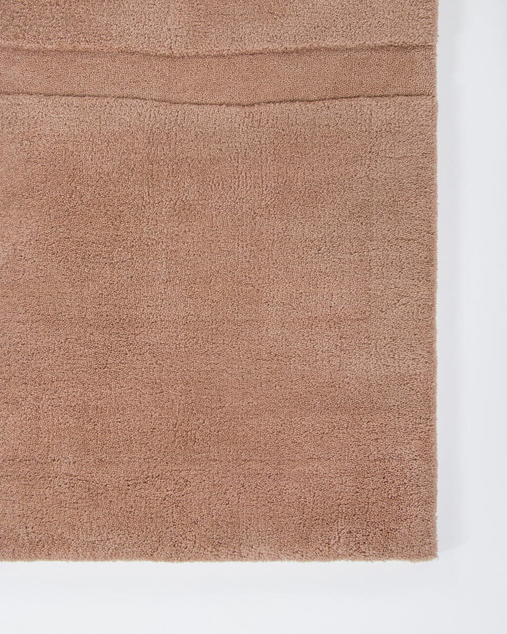 Baya Strata NZ wool floor rug in Clay, close view of a corner showing the pile and a horizontal ridged line.