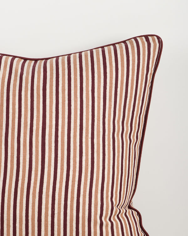 Baya Strato Cushion in Oxblood, close view of a top corner showing the stripes and burgundy piped edge.