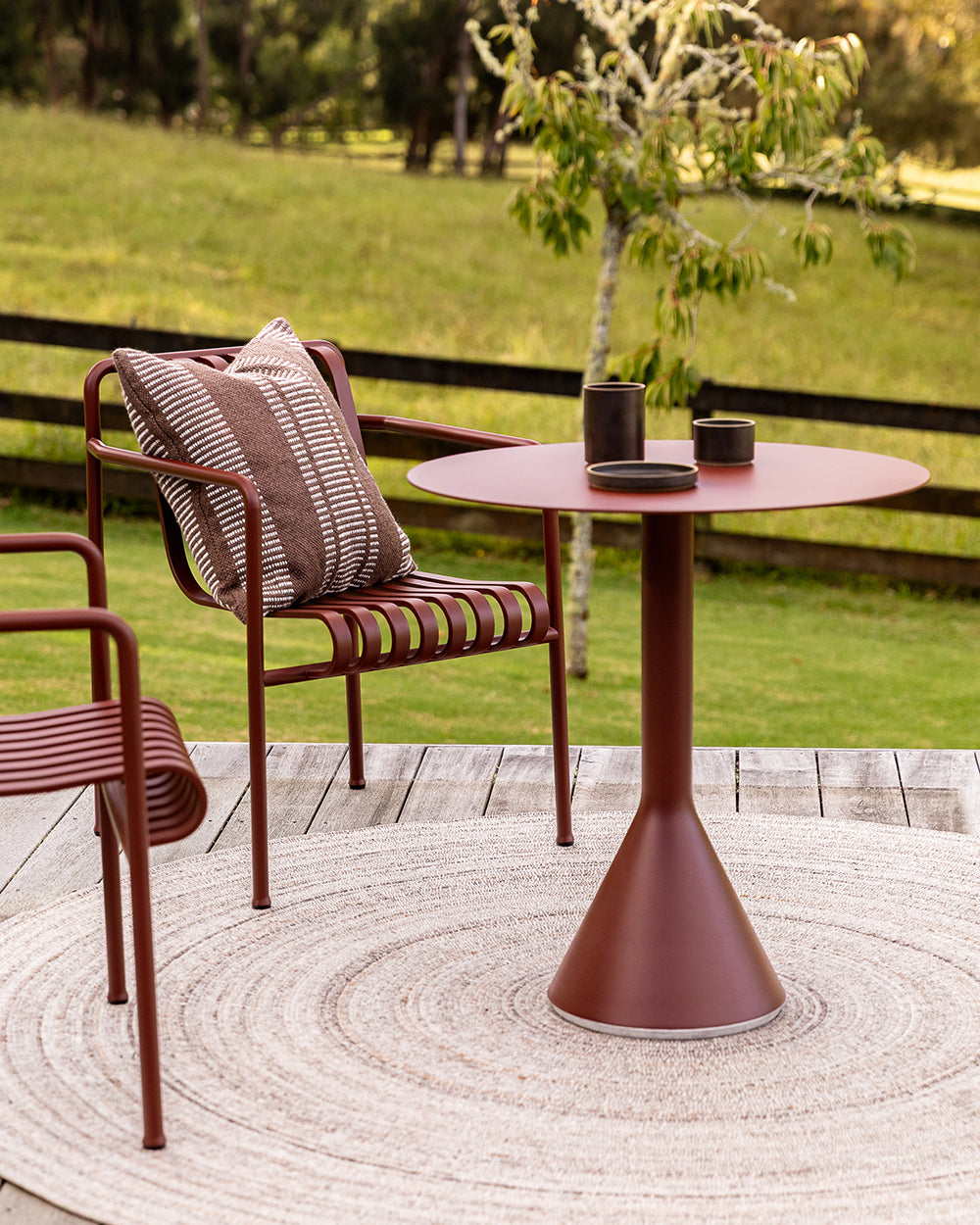 Baya Swell Outdoor Cushion in Chocolate, close styled view on an outdoor chair beside a pool.