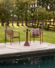 Baya Swell Outdoor Cushion in Chocolate, styled poolside on an outdoor chair beside a bistro table.