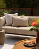 Baya Tide Outdoor Cushion in Almond styled on an outdoor sofa, a closer view beside a grey patterned cushion.