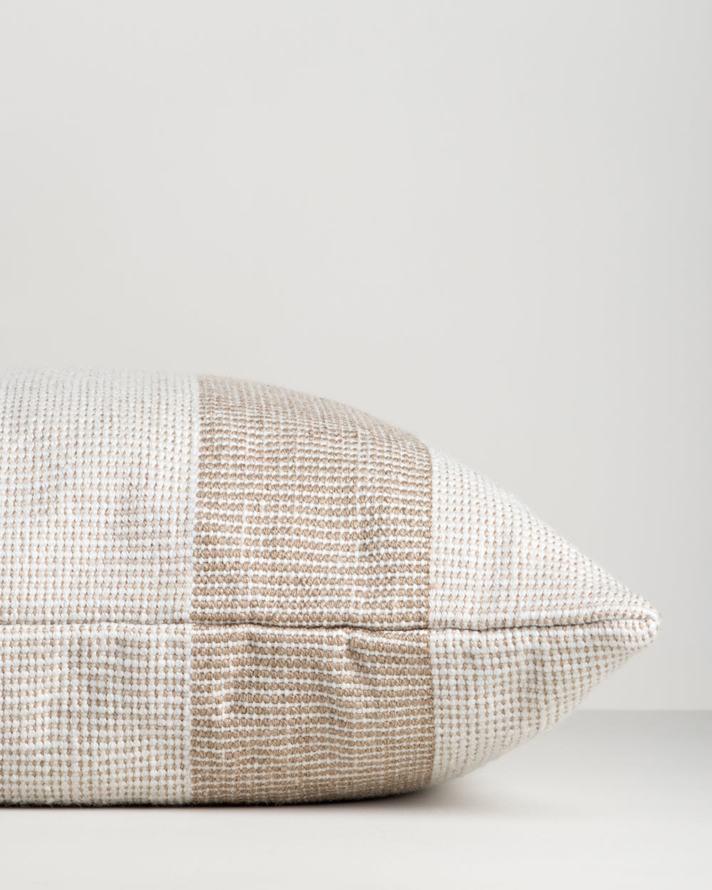 Side view of the Baya Tide Outdoor Cushion in Almond, showing the handwoven stripe wrapping the cushion edge.