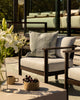 Baya Tide Outdoor Cushion in Eucalyptus styled on an outdoor lounge chair, with white lilies in the foreground.