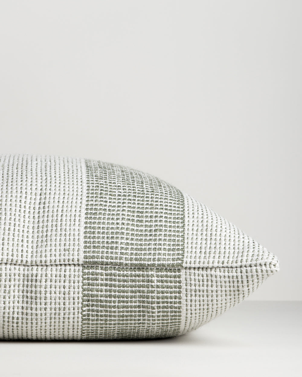 Side view of the Baya Tide Outdoor Cushion in Eucalyptus, showing the handwoven stripe wrapping the cushion edge.