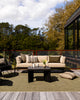 Baya Tide Outdoor Cushion in Mangrove styled on an outdoor sofa, a closer view with flowers and cups.