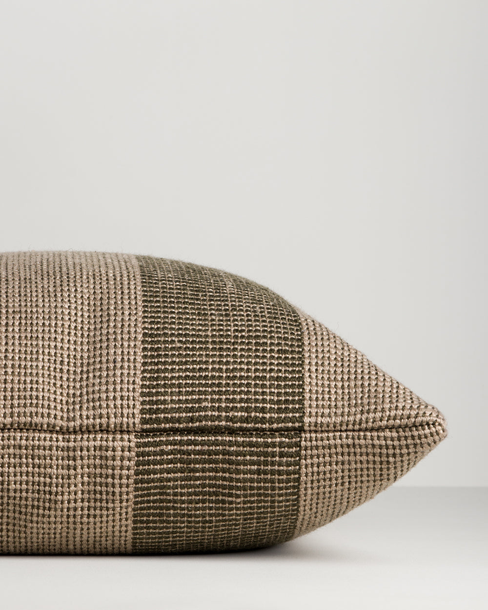 Side view of the Baya Tide Outdoor Cushion in Mangrove, showing the handwoven stripe wrapping the cushion edge.