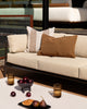 Baya Tide Outdoor Cushion in Tobacco styled on an outdoor sofa with a solid brown Baya cushion.