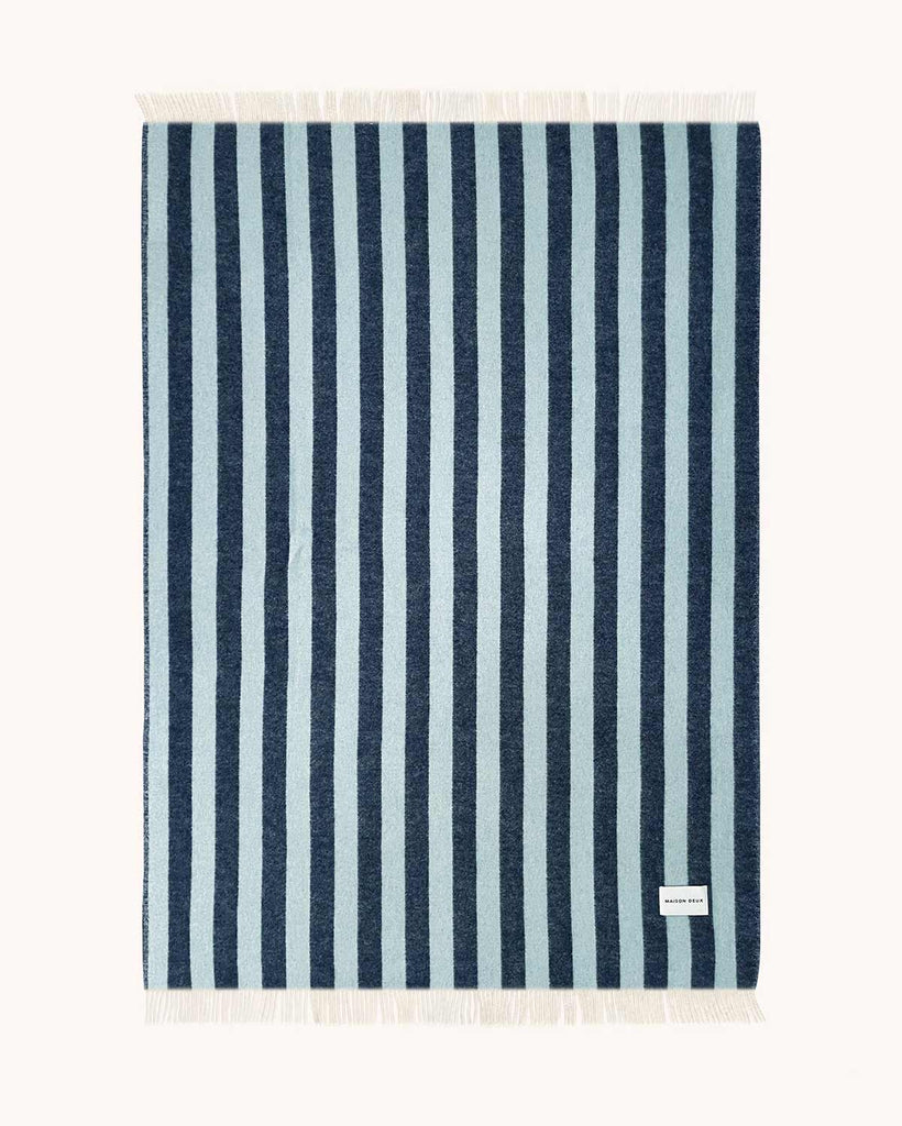A full image of the backside of a throw blanket, spread to see the full pattern of dark blue and ice blue stripes.