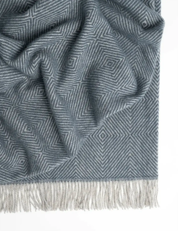 A thick and large, blue wool throw blanket with fringe
