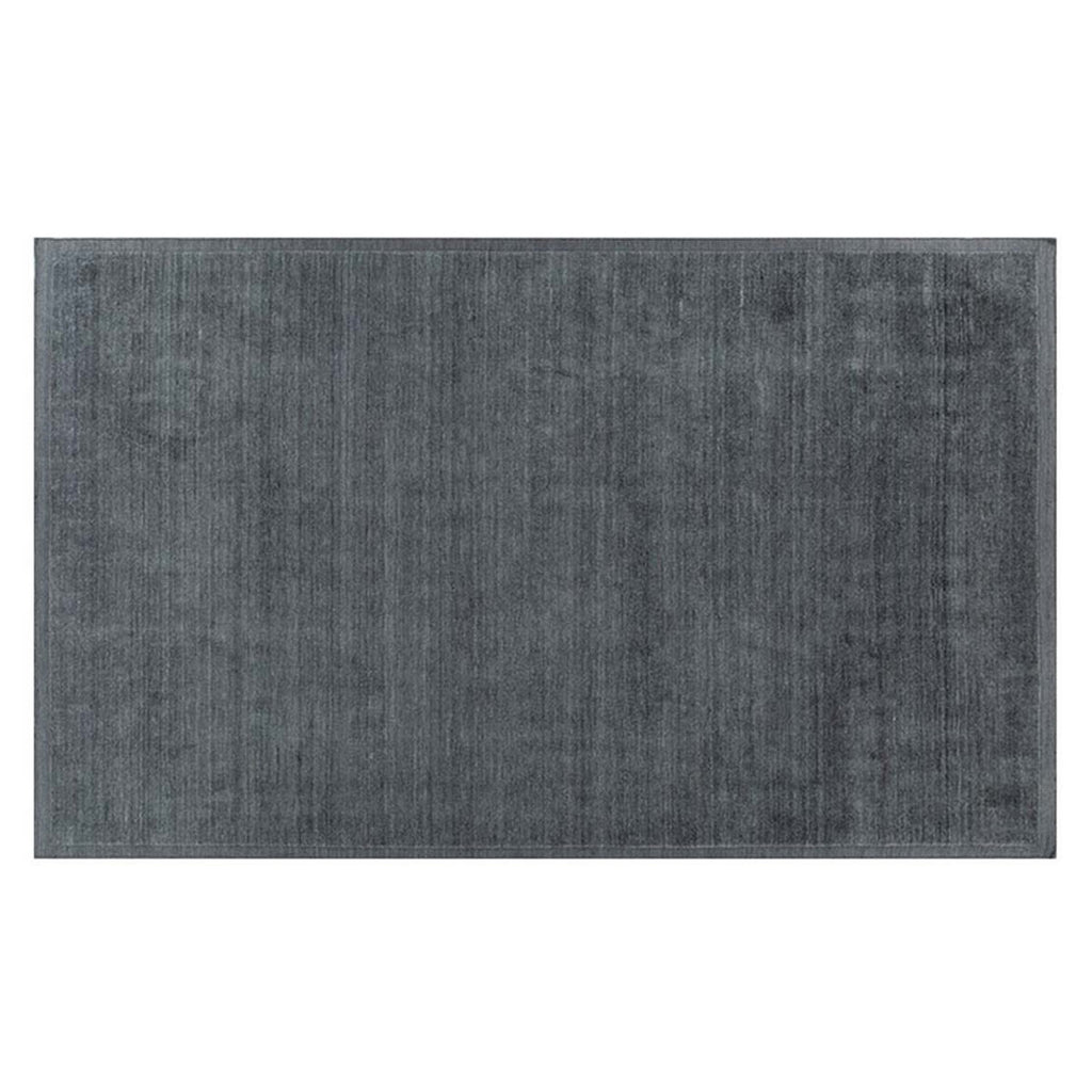 Full view of a handmade wool rug in a neutral, muted blue shade, with an indented border adding interest. 