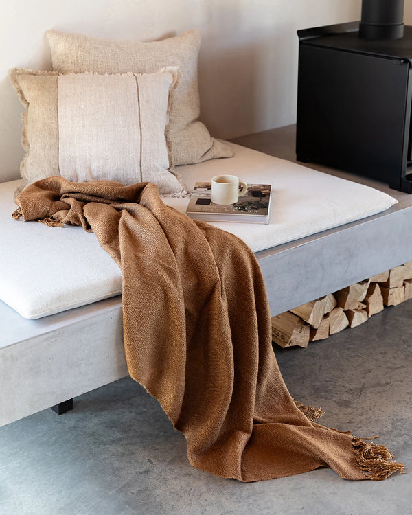 Brown throw blanket in colour 'cinnamon' draped on a seat in a modern living room