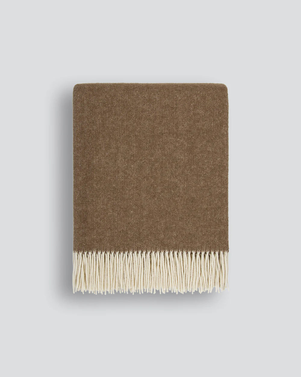 Brown wool blanket in a micro herringbone pattern with fringe on a light grey background