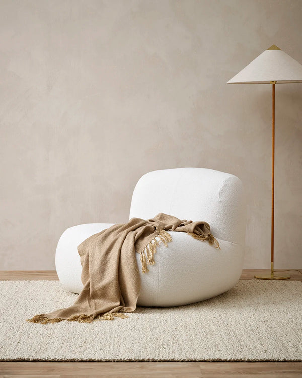 Baya light brown 'Richmond Cumin' throw blanket draped on a chair in a contemporary living room
