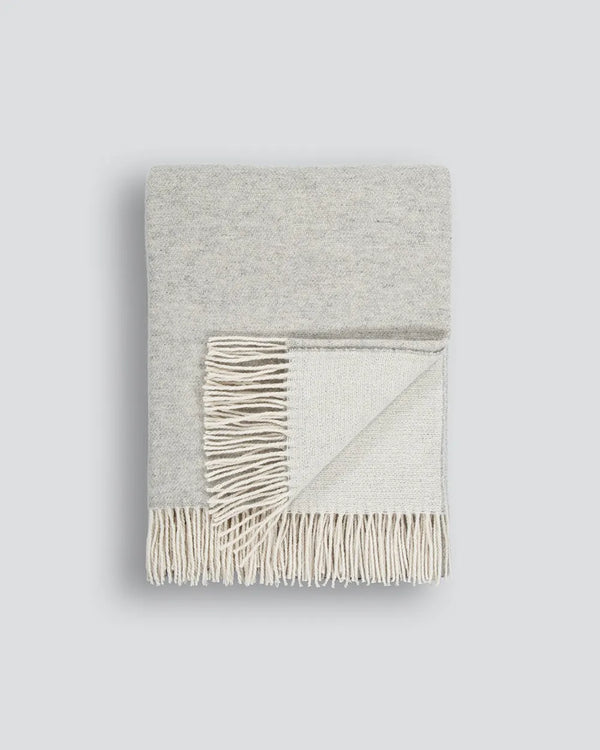 Light grey merino-blend throw blanket with tasselled fringe