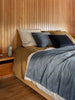 Città Cotton Velvet Quilt in Cod on a bed in a timber-panelled bedroom, layered with linen bedding
