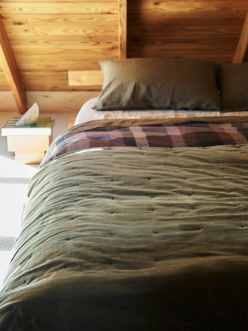 Città Cotton Velvet Quilt in Ivy on a bed in a timber-lined attic bedroom