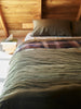 Città Cotton Velvet Quilt in Ivy on a bed in a timber-lined attic bedroom