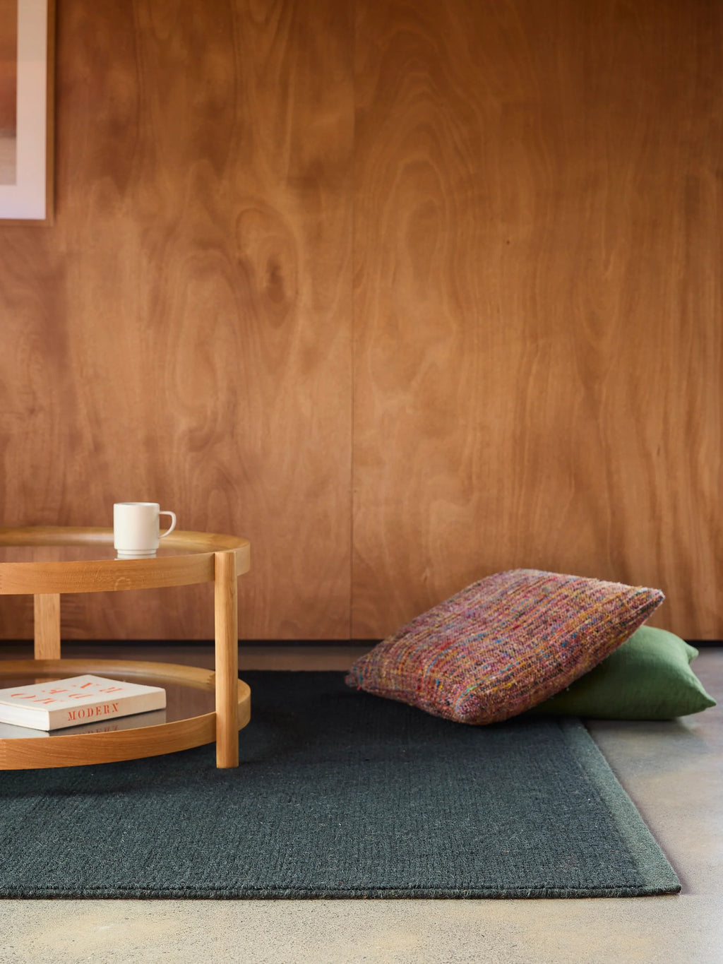 Città Joni Wool Mat in Baltic/Pine, styled against a wood-panelled wall in a living space.