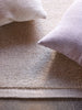 Città Joni Wool Mat in Oatmeal, close view styled with cushions in a living space.