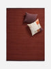 Città Joni Wool Mat in Paprika/Mulberry, overhead view styled with cushions.