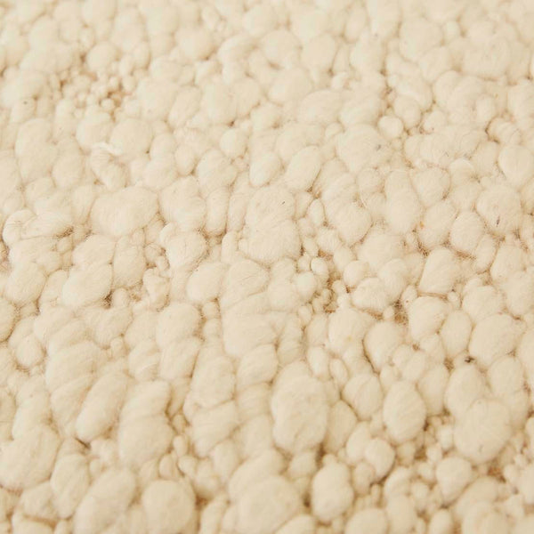 Close up of the weave of a textural wool blend boucle style rug by Globe West and Soren Liv NZ in shades of warm ivory and cream. 