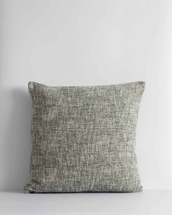 A textural cushion in shades of sage green and ercu, with a prominent weave, by Baya. 