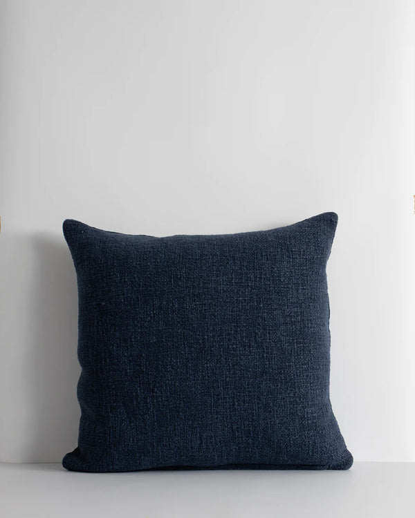 A deep blue cushion with a textural weave and a subtle lustre